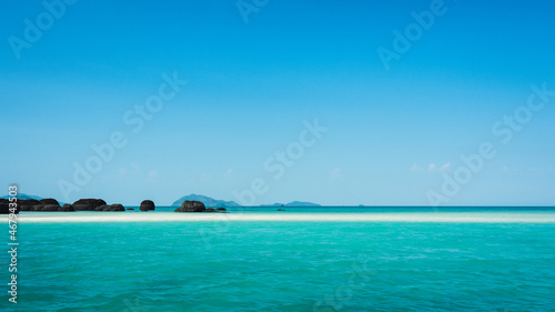 Peaceful white sand bar with iconic black volcanic rock of Koh Kham Island and crystal clear turquoise water. Near Koh Mak Island, Trat Province, Thailand.
