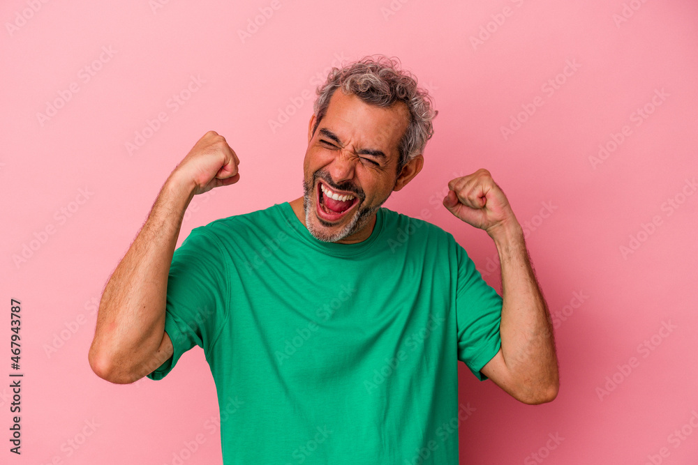 Middle age caucasian man isolated on pink background raising fist after a victory, winner concept. Middle age caucasian man isolated on pink background raising fist after a victory, winner concept.