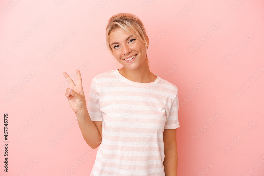 Young Russian woman isolated on pink background showing victory sign and smiling broadly. Young Russian woman isolated on pink background showing victory sign and smiling broadly.