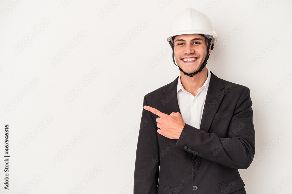 Young architect caucasian man isolated on white background smiling and pointing aside, showing something at blank space.