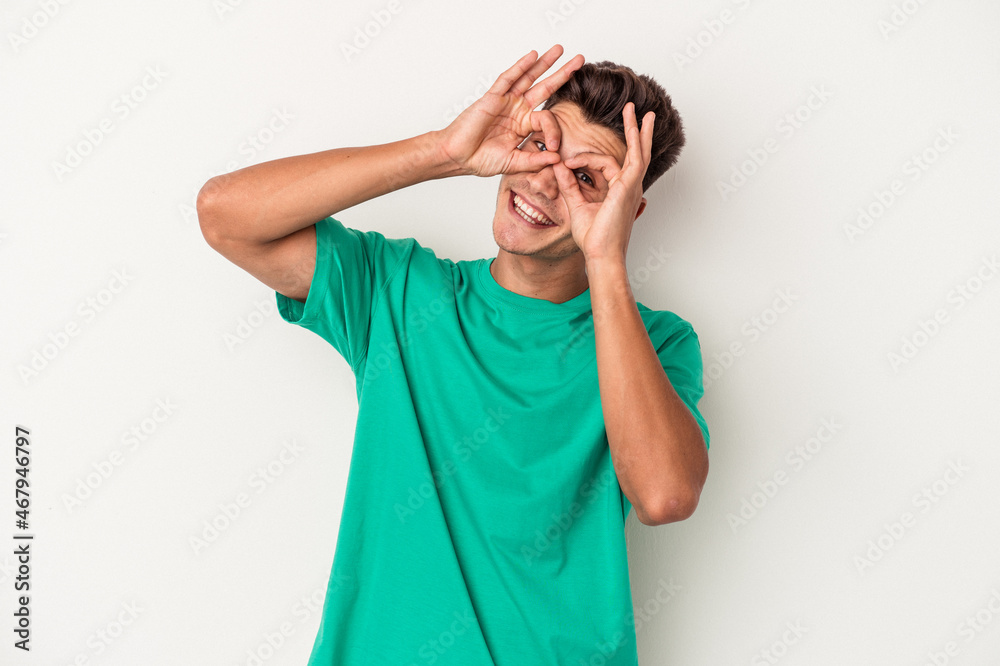 Young caucasian man isolated on white background showing okay sign over eyes Young caucasian man isolated on white background showing okay sign over eyes