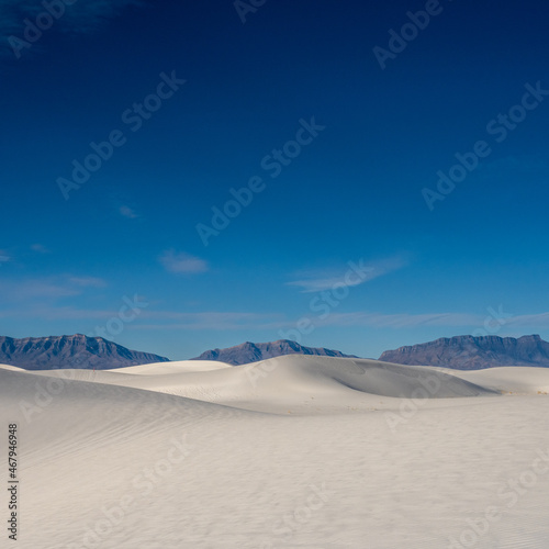 Smooth Dunes and Jagged Mountains Below Deep Blue Sky