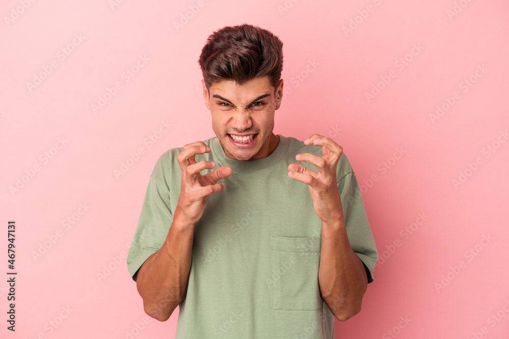 Young caucasian man isolated on pink background upset screaming with tense hands. Young caucasian man isolated on pink background upset screaming with tense hands.