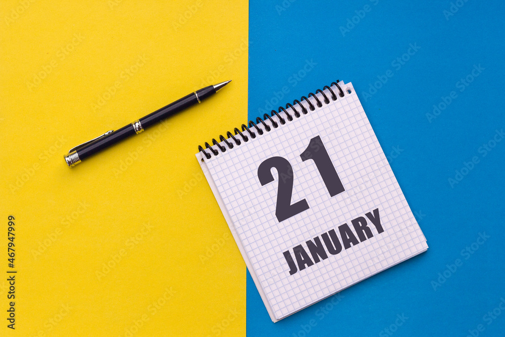 January 21th. Day 21 of month. Calendar date. Notebook with a spiral and pen lies on a yellow-blue background January 21th. Day 21 of month. Calendar date. Notebook with a spiral and pen lies on a yellow-blue background