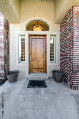 Front entrance of a house with wooden door with two side panels and arched transom window