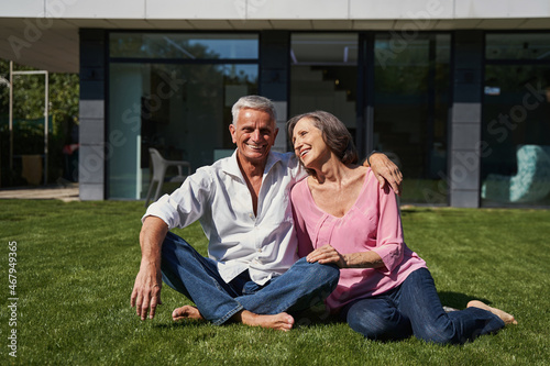 Elderly man and aging lady sitting together before house