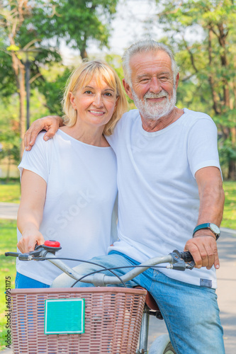 senior couple happy together riding bicycle outdoor in park in summer