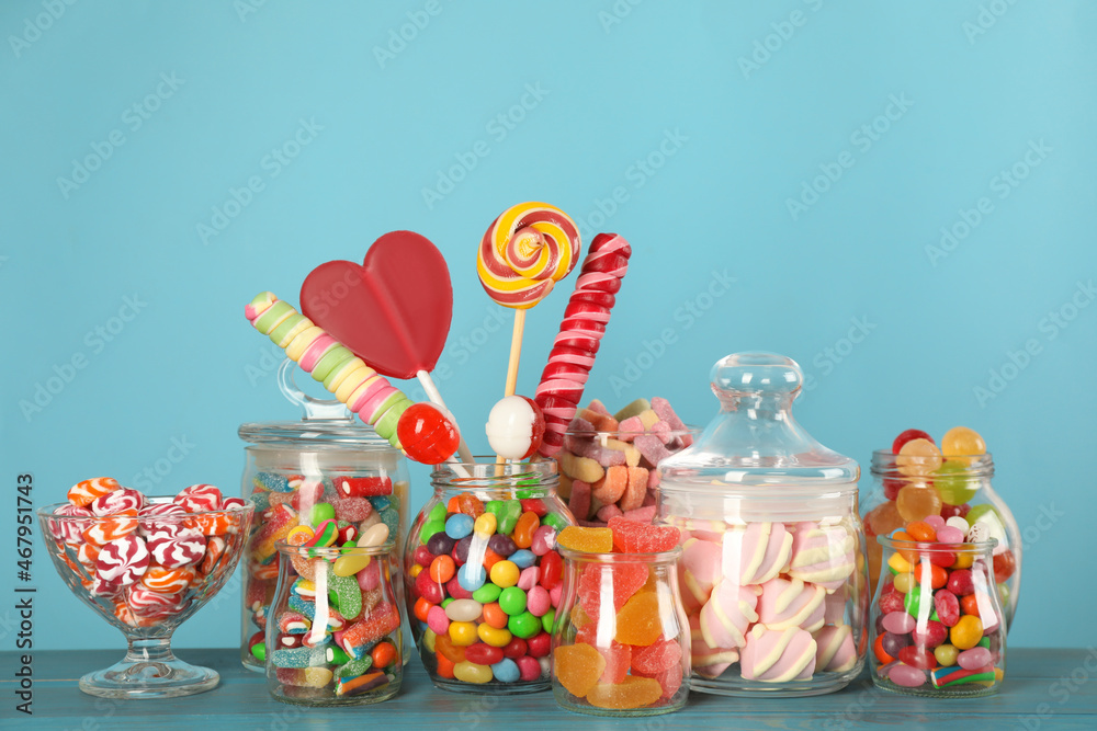 Fototapeta premium Jars with different delicious candies on turquoise wooden table