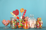 Jars with different delicious candies on turquoise wooden table