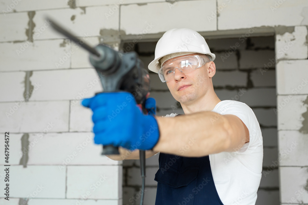 Close-up of a drill in the hands of a professional builder.