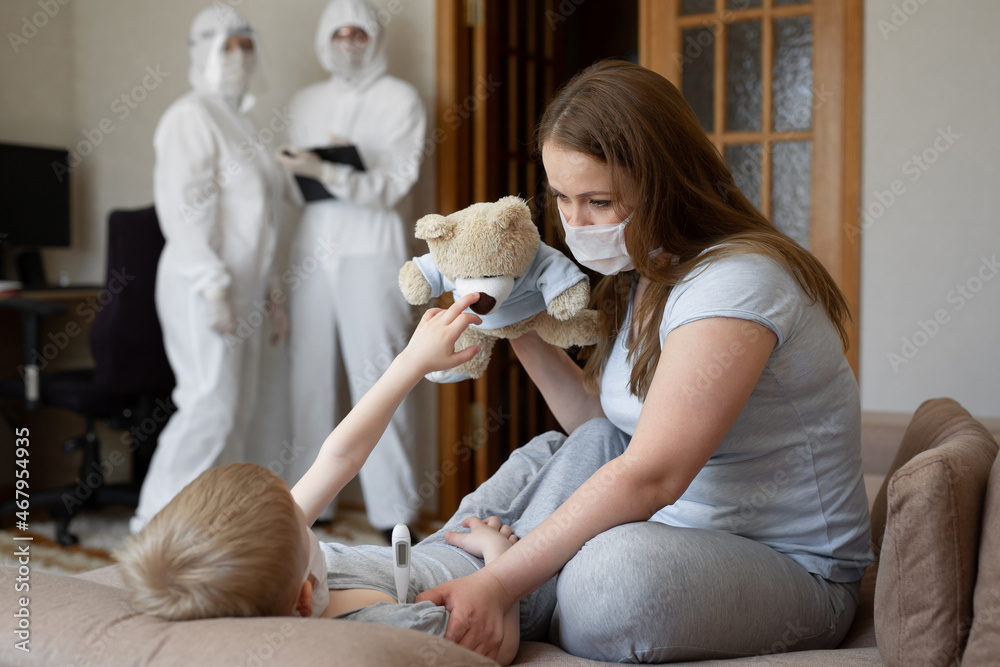 Mom measures baby's temperature. Doctors in protective suits at sick patients at home. Coronavirus, covid-19. Mom measures baby's temperature. Doctors in protective suits at sick patients at home. Coronavirus, covid-19.
