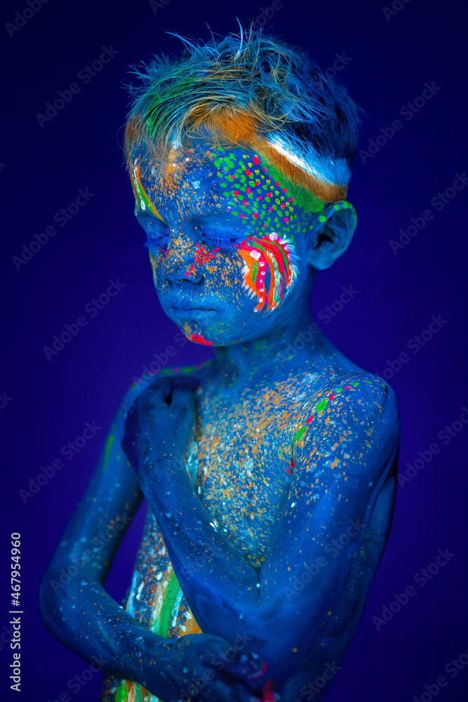Portrait of a neon child boy posing in UV