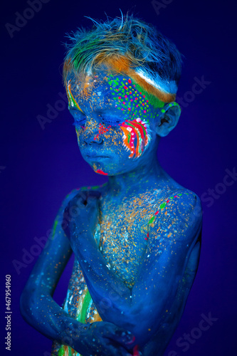 Fototapeta Naklejka Na Ścianę i Meble -  Portrait of a neon child boy posing in UV