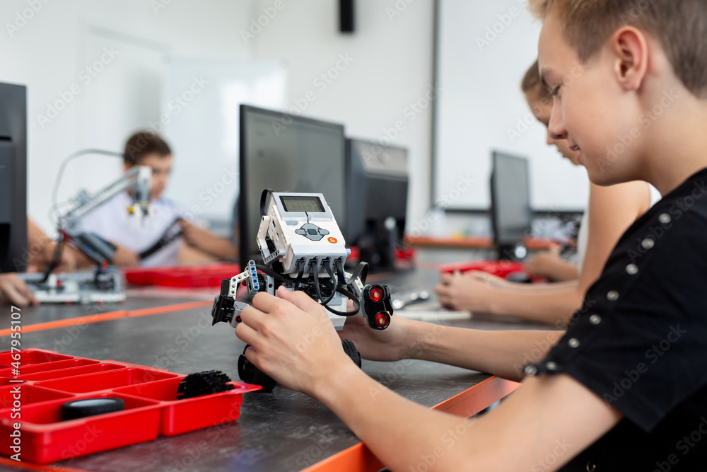 Concentrated teen child programming robot at class, stem education concept Concentrated teen child programming robot at class, stem education concept