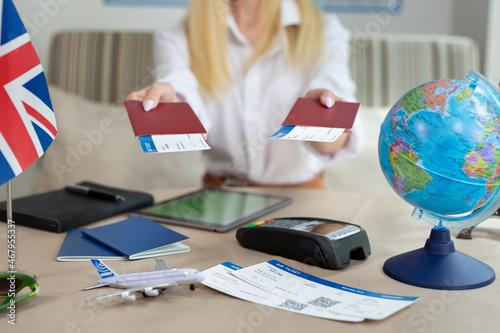A close-up of a passport with tickets in the hands of a female tour operator in the office.