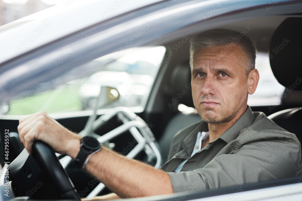 Portrait of adult man with disability driving car, wheelchair in background, copy space