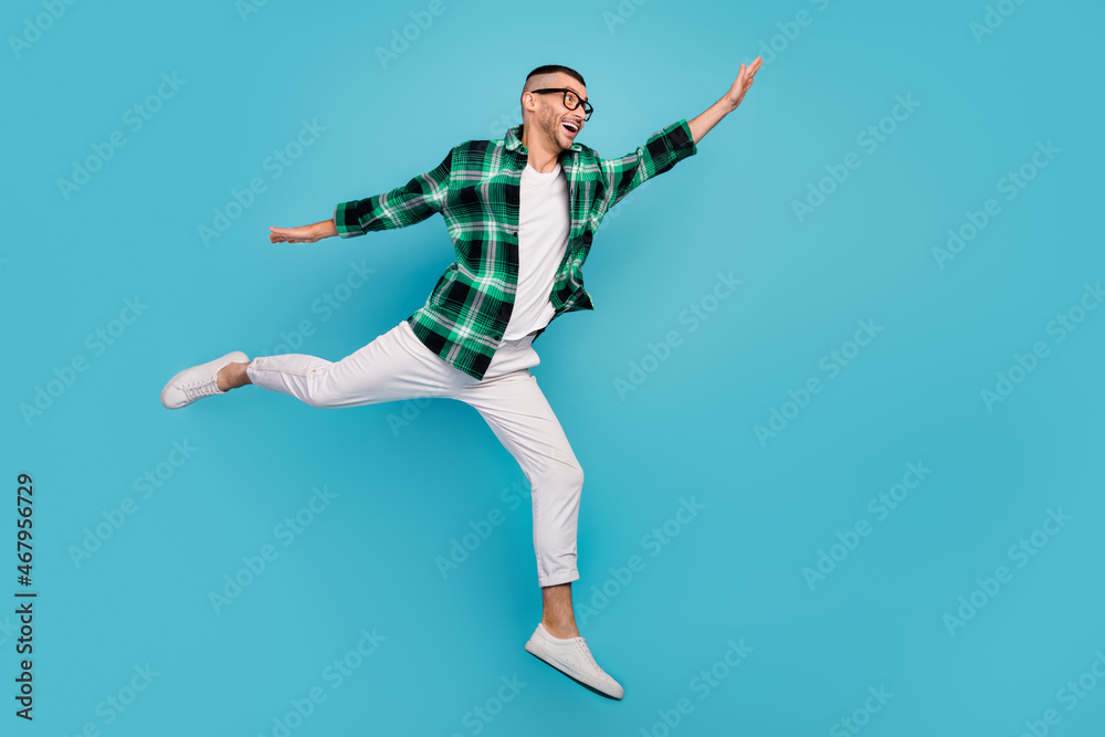 Full length photo of happy young amazed man look empty space jump up isolated on pastel blue color background