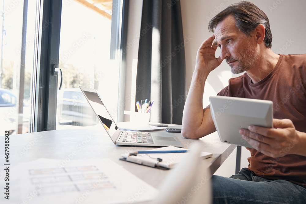 Fototapeta premium Serious aged man making calculations in office