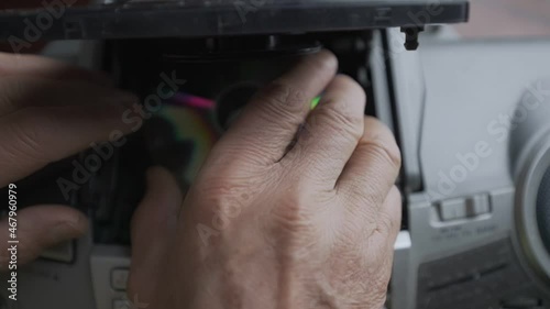 Older man with wrinkled hand changing CD disk in retro music boombox top view. Vintage audio and stereo equipment collection. photo