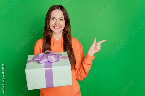 Portrait of lovely lady receive present direct finger empty space on green background