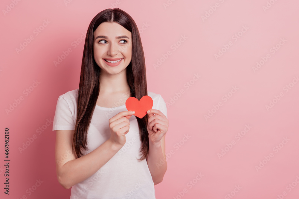 Portrait of attractive lovely cheerful girl holding in hands small little heart look empty space isolated over pink background Portrait of attractive lovely cheerful girl holding in hands small little heart look empty space isolated over pink background