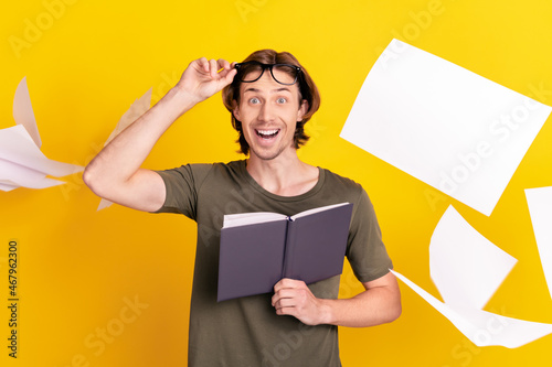 Photo of young excited man happy positive smile read book study fly air paper isolated over yellow color background