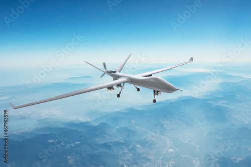 Unmanned spy military drone flies over mountains at day time.