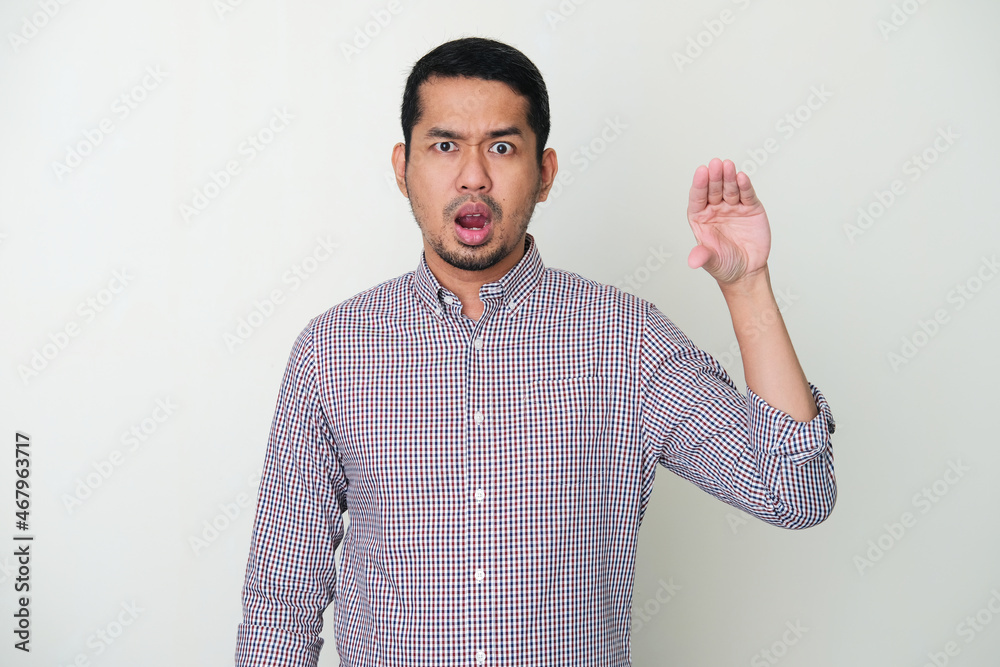 Adult Asian man showing uncomfortable expression with his hand imitate talking mouth Adult Asian man showing uncomfortable expression with his hand imitate talking mouth