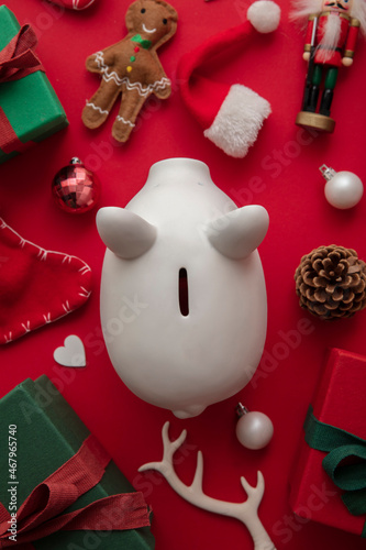 Festive Christmas financial savings concept. White piggy bank money box with presents and decorations
