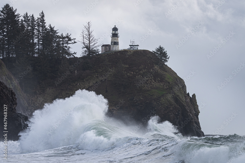 Powerful ocean waves crashing under light house during king tide storm on the Washington Coast