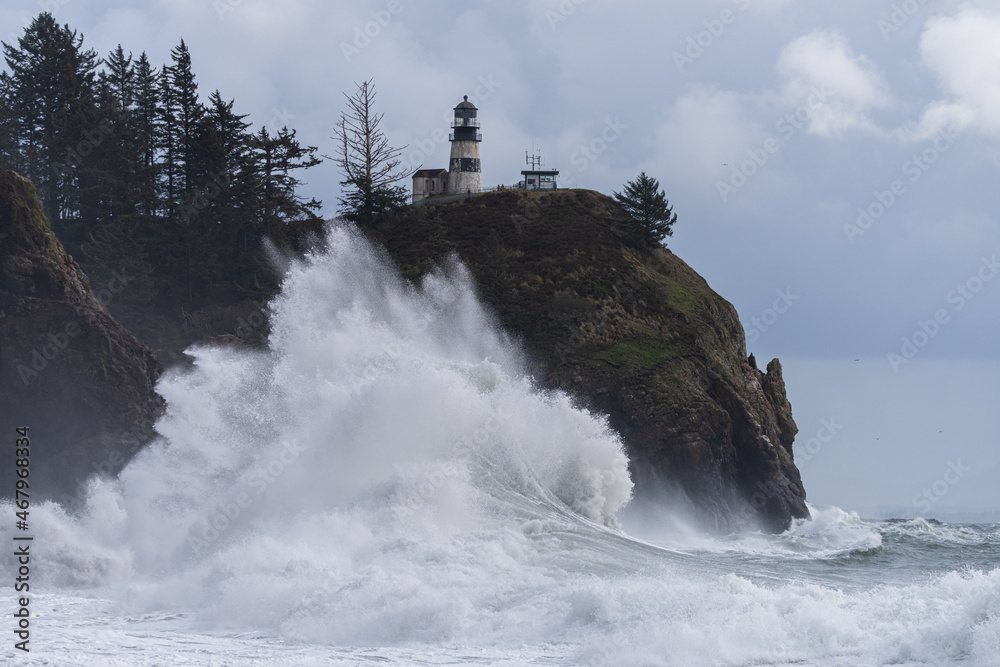 Gigantic king tide waves crashing under light house during coastal storm season at Cape Disappointment State Park, Washington 
