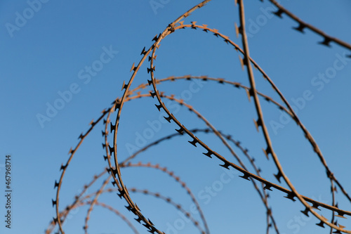 usty barbed wire over blue sky background, close-up photo