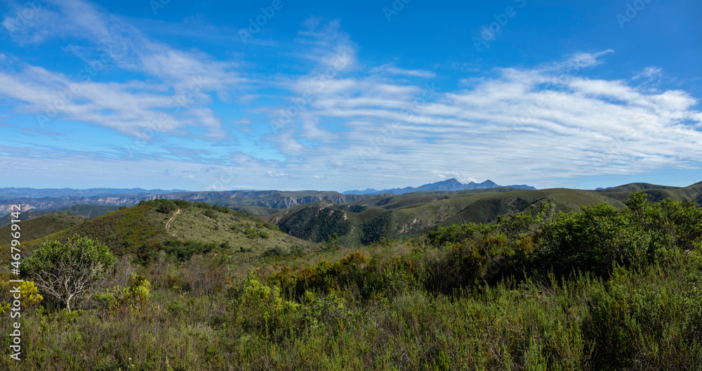 Green hills and blue mountains with thin white clouds