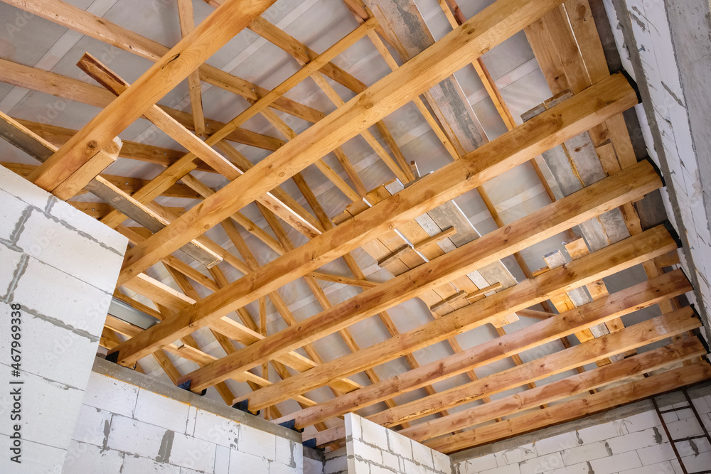 New construction of a wooden roof. Wood girder beams for new roof  construction at construction site Stock 写真 | Adobe Stock
