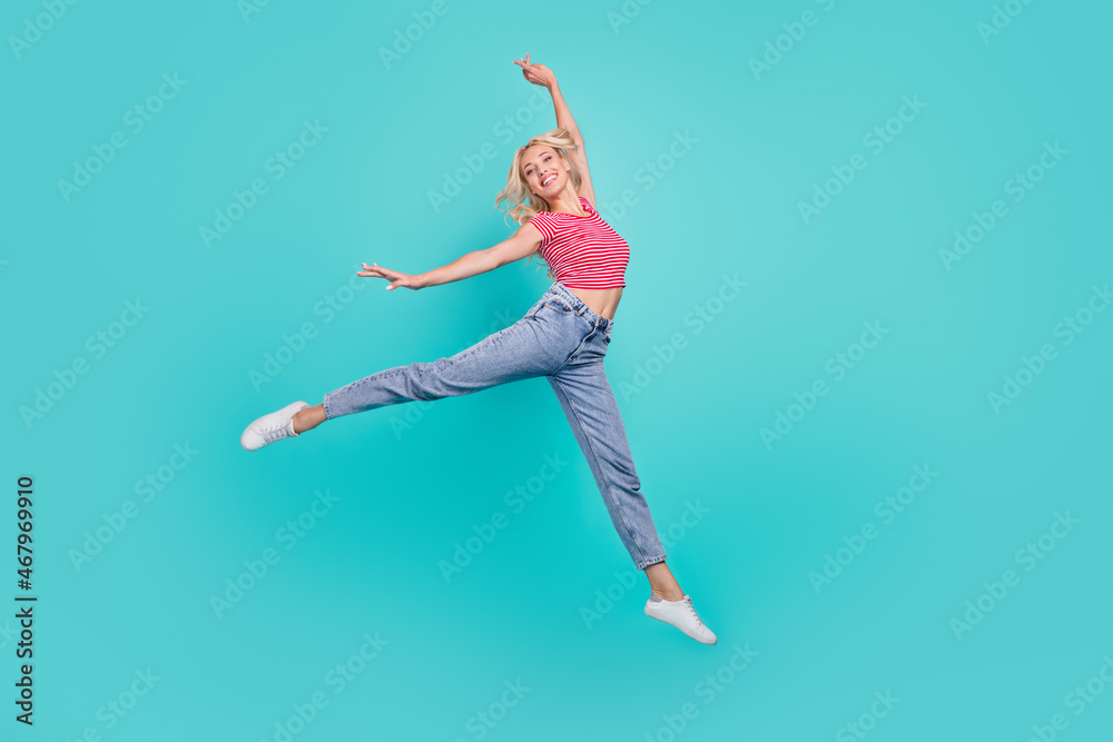 Photo of funky adorable young woman dressed red t-shirt smiling jumping high isolated teal color background Photo of funky adorable young woman dressed red t-shirt smiling jumping high isolated teal color background