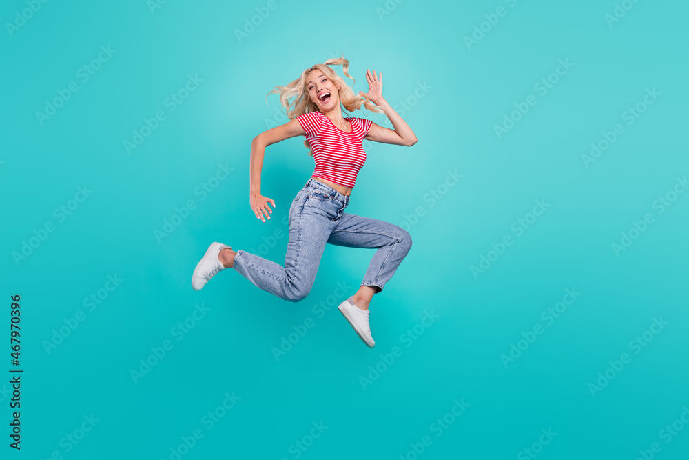Photo of sweet funny young woman dressed red t-shirt smiling jumping high running fast isolated teal color background