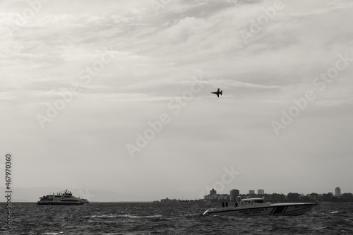 boat on the gulf of Izmir as f 16 fighter jet Turkish Air Force Flying in 9 Eylul celebrations above photo
