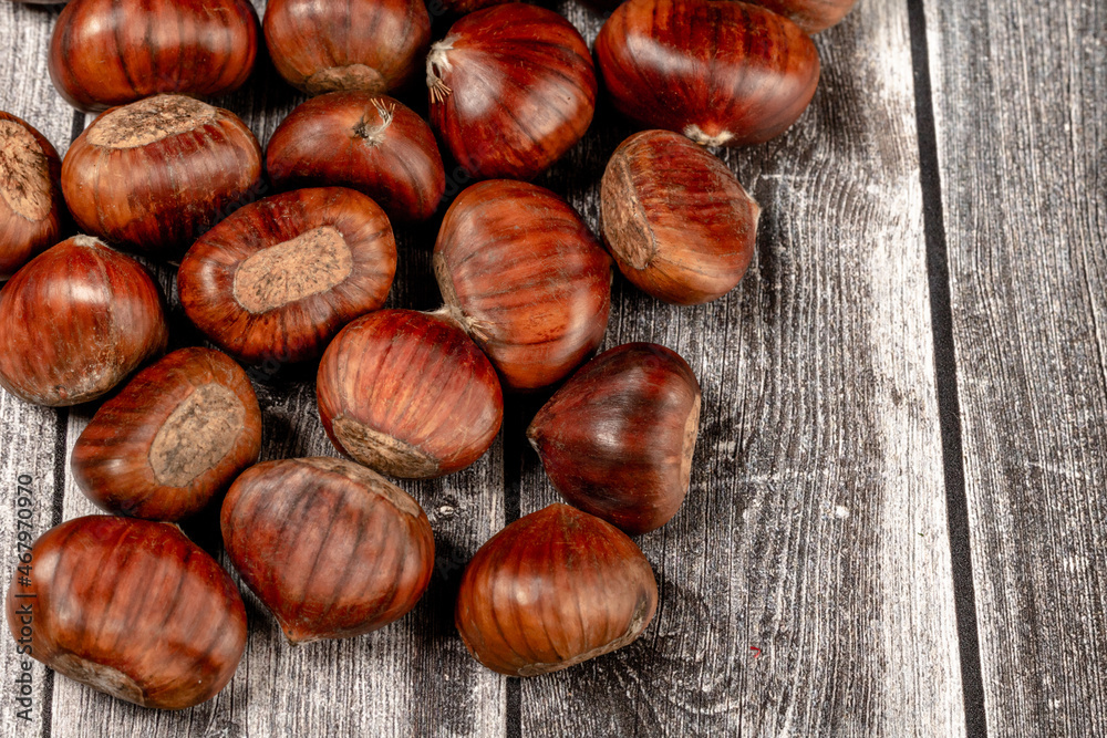 some raw chestnuts, marron (Castanea sativa), a classic autumn fruit, on light colored wooden rustic background. some raw chestnuts, marron (Castanea sativa), a classic autumn fruit, on light colored wooden rustic background.