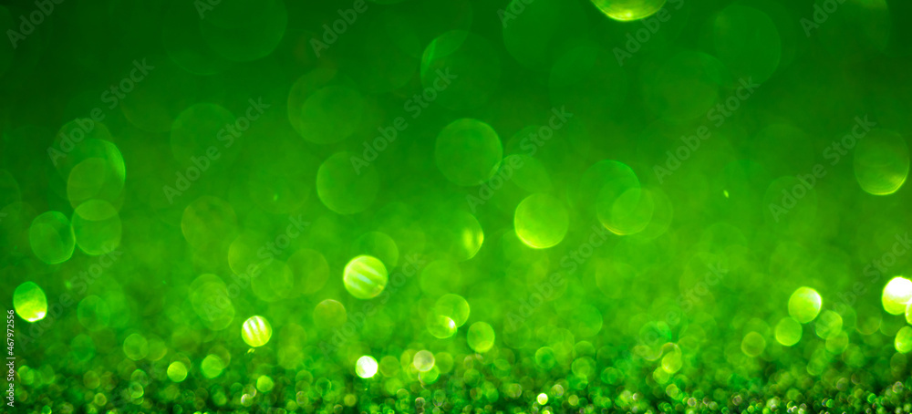 Fototapeta premium Green Christmas lights background, banner design. Shiny glowing surface with bokeh, abstract defocused glitter with sparkles
