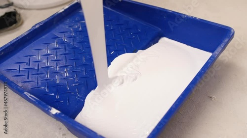 White interior paint is poured into the container. Home painting 