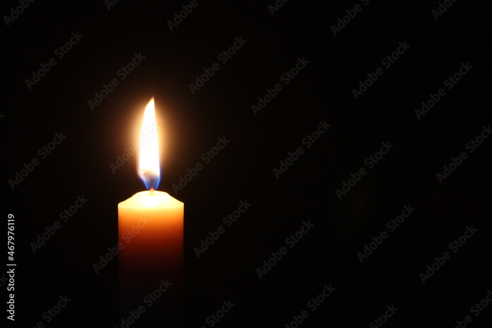 Flame of one candle on a horizontal black background Candle on the left side of the photo with free space for text on the right Flame of one candle on a horizontal black background Candle on the left side of the photo with free space for text on the right