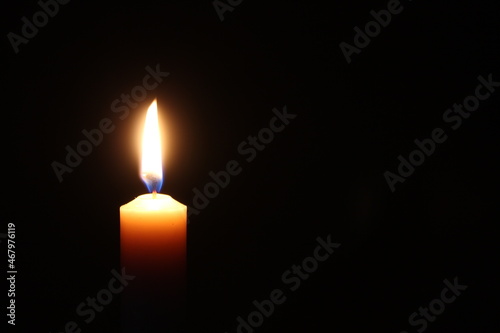 Flame of one candle on a horizontal black background Candle on the left side of the photo with free space for text on the right