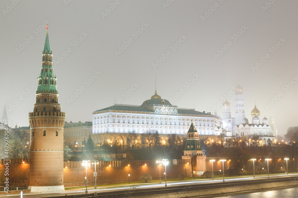 Moscow, Russia.  Classical view of the Moscow Kremlin: Vodovzvodnaya tower, Great Kremlin palace and temples. Shot from  Bolshoy Kamenny bridge. November. Night. Little fog