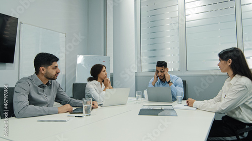 Fotografie Disgruntled young arab male boss scolding employees for bad work at meeting of d