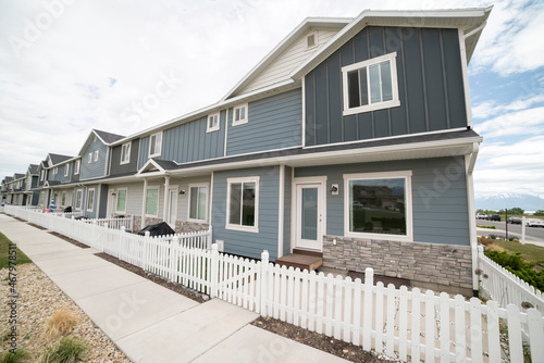 Facade of townhouses with gray sidings and picket fence