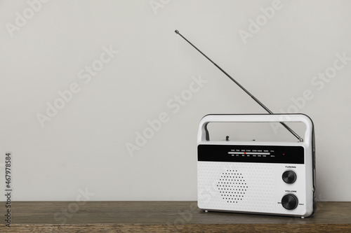 Retro radio receiver on wooden table against light grey background. Space for text