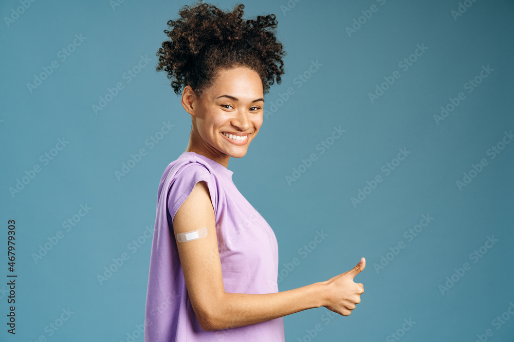 Young multiracial woman showing arm with adhesive plaster bandage after getting vaccinated for coronavirus Young multiracial woman showing arm with adhesive plaster bandage after getting vaccinated for coronavirus