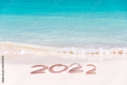 2022 written on the sand of a tropical beach, travel new year card