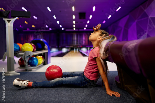 Fotografie Girl sitting on the floor in bowling alley