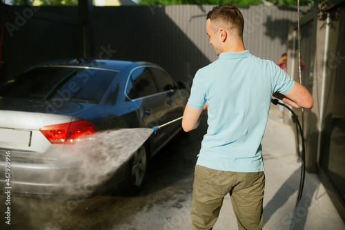Man holds high pressure water gun, car wash